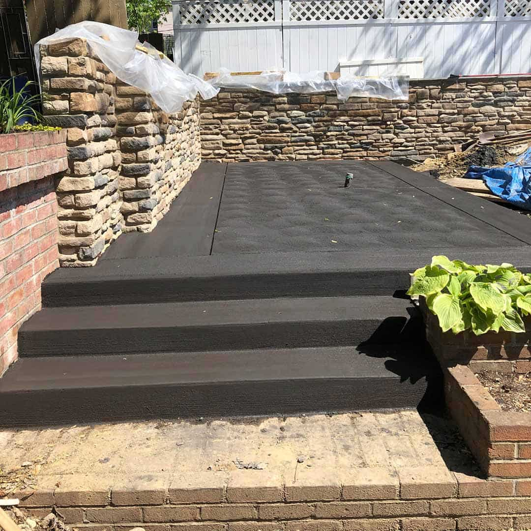 Newly constructed concrete sun deck with decorative stone retaining walls